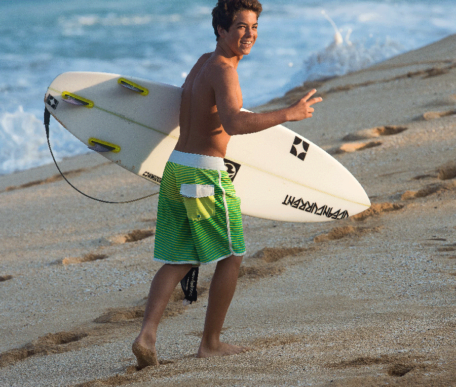 Surfer carrying a board on the beach